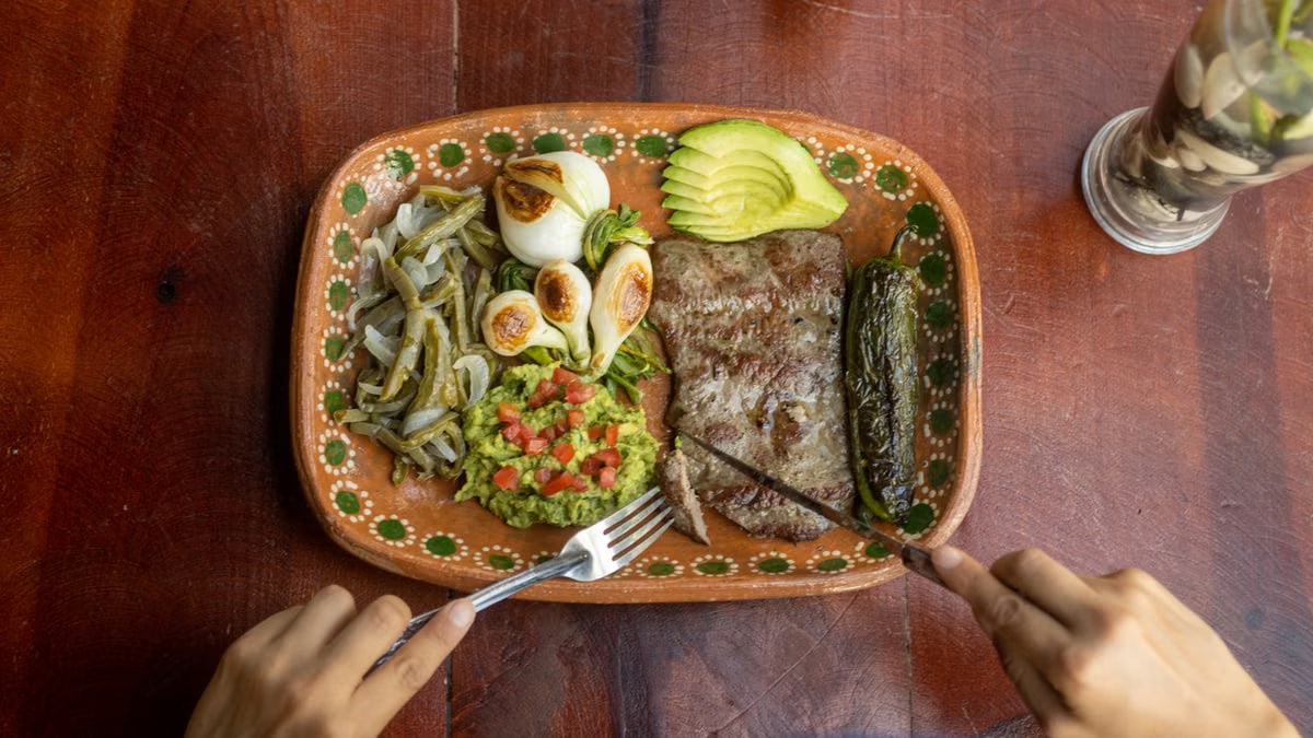 Authentic Mexican meal featuring grilled steak, avocado, and vegetables on a ceramic plate.